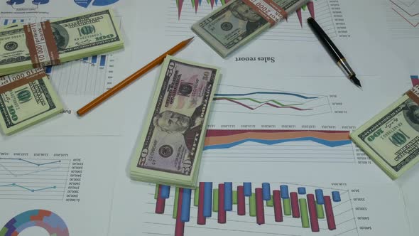 Business Graphs And Money On The Desk In A Modern Office