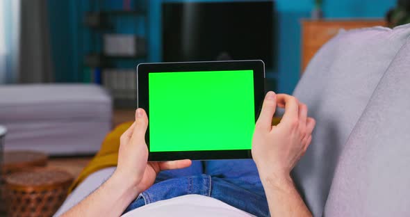 Young Man Using with Green Mockup Screen Tablet Computer in Horizontal Landscape Mode