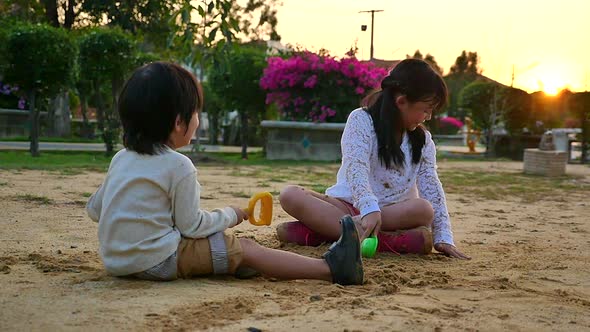 Asian Children Playing Sand In Playground Under Sunset