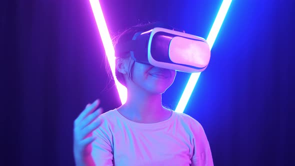 Excited Asian Young Girl Using Virtual Reality Headset And Use Hand Slide With Neon Light