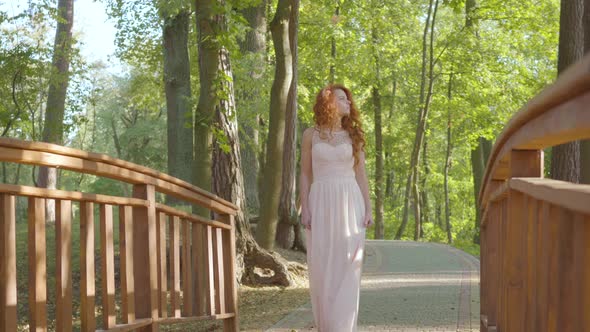 Young Readhead Girl Walking in the Park. Pretty Caucasian Woman in Long Light Dress Resting in the