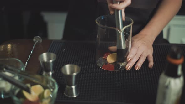 Close up shot of female barkeeper swirling crushed lime and orange for fresh cocktail