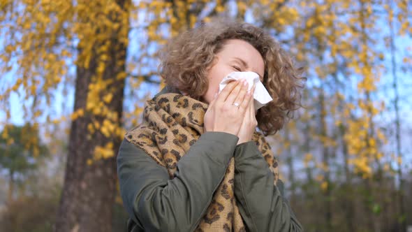 Woman Sneezing With Tissue Having Flu Or Allergy Outdoors