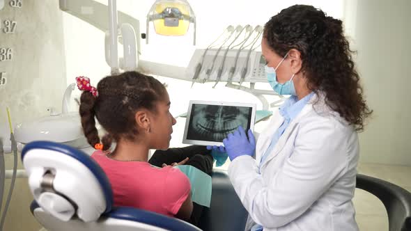 Female Stomatologist Showing Dental Xray to Girl