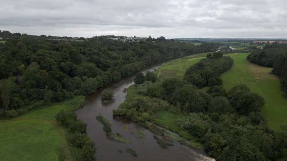 Drone shot of a large river flowing through green fields in Ireland.
