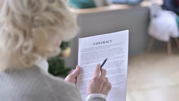 Rear View of Focused Old Woman Reading Contract