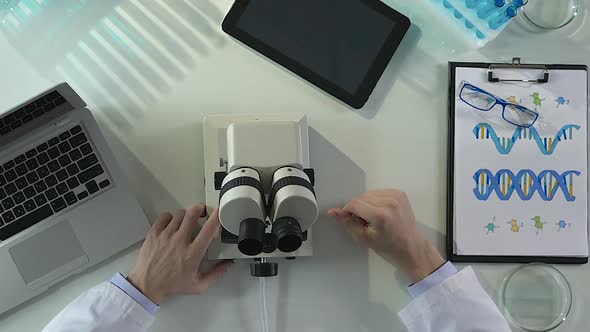 Male Scientist Preparing His Workplace and Microscope for Research Work in Lab