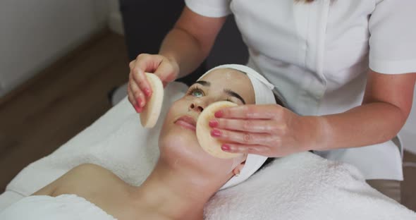 Caucasian woman lying back while beautician gives her a facial