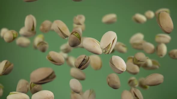 Closeup of the Salted Pistachios Flying Up and Rotating on a Green Background