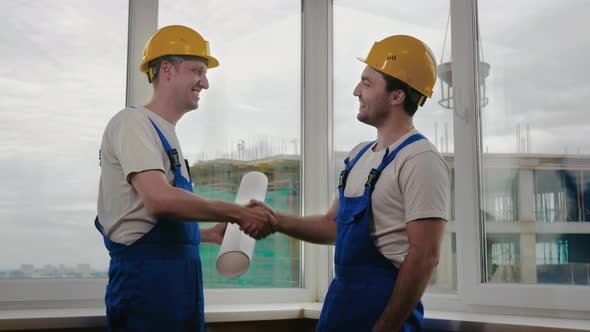 Handsome Construction Workers in Protective Helmets Shaking Hands