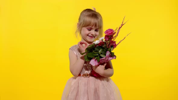 Little Child Girl with Fashion Makeup Standing with Bouquet of Flowers Isolated on Yellow Background