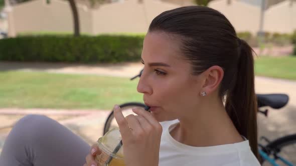 Young Woman Drinking Juice in the Park