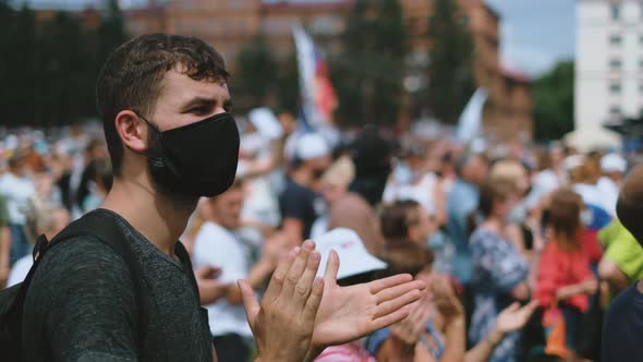 Clapping Protester Man in Face Mask in Political Rally Crowd on City Streets