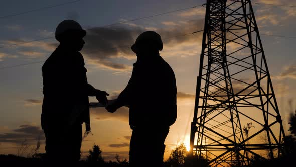 Engineers Shaking Hands at the Construction of High-voltage Power. Teams Engineer Looking Discussing