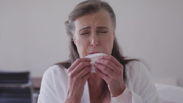 Sick woman with tissue sneezing at home