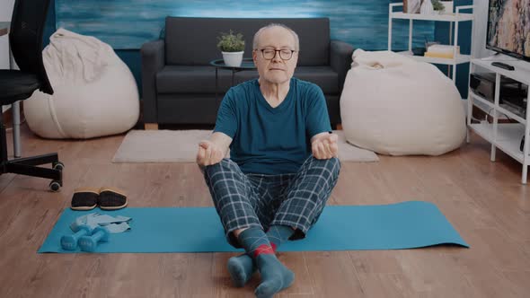 Aged Man Doing Meditation While Sitting in Lotus Position