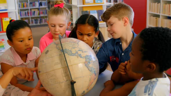 Asian female teacher teaching the kids about the globe at table in school library 4k