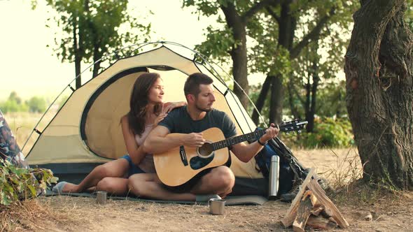 Young Couple Playing on Guitar in the Forest