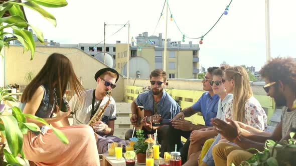 Beautiful girl taking photos of friends at party on a rooftop terrace