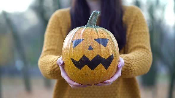 Woman Holding Jack-o-lantern Pumpkin in Autumn Park