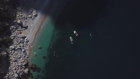 Top view of two standing motor boats and water scooter around them on emerald beach in Black sea 4k