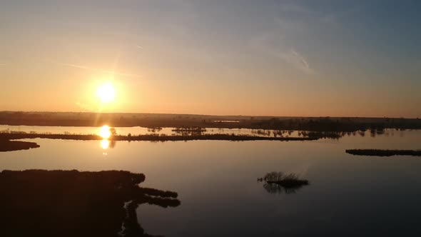 Panning aerial shot sun setting golden hour teal orange sky reflection