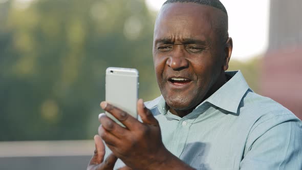 Emotional Senior African American Man Making Video Call Looking at Smartphone Camera Talking on