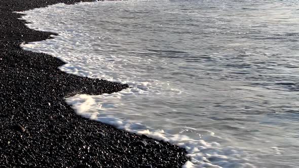 Close up of black pebble beach and waves