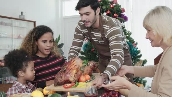 family having holiday dinner and cutting turkey Thanksgiving Celebration