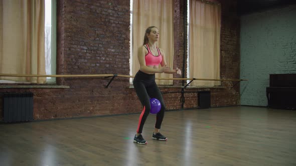 Fit Female Doing Squats with Medicine Ball at Gym