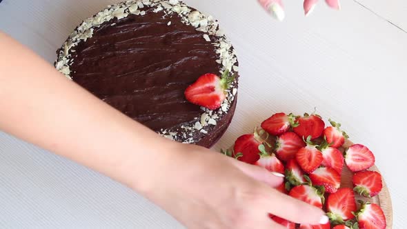 A Woman Decorates A Cake With Strawberries.