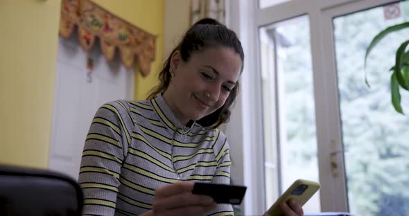 Woman with mobile phone and credit card on the sofa making online purchases o