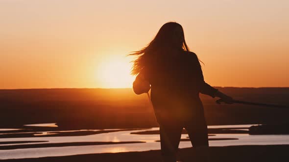 Young Woman in Black Clothes Training with Two Swords While Sunset on Nature