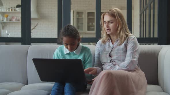 Smiling Mom and Daughter Networking on Laptop