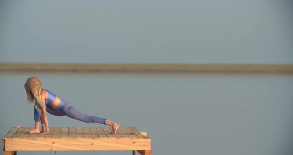 Sporty Woman is Stretching and Exercising During Sunset on a Lake