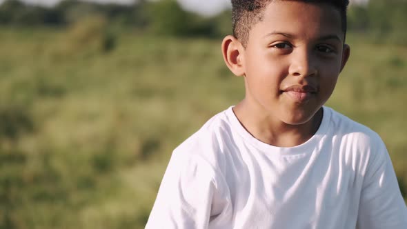 African Boy in a White Shirt with a Plane in Hands on Field