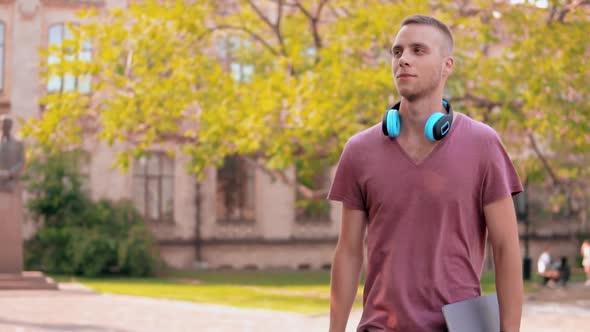 Student Walking in Campus Area Holding Book