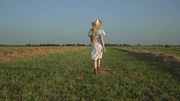 A Young Attractive Rural Woman Walks Through a Field with Mowed Grass Rustic Lifestyle