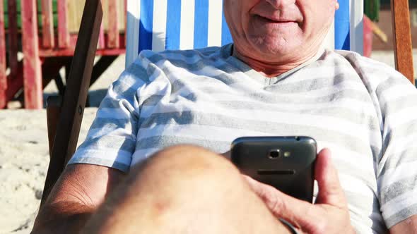 Senior man talking on mobile phone while relaxing on sunlounger