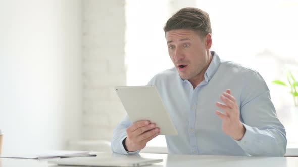 Man Reacting to Loss on Tablet in Office