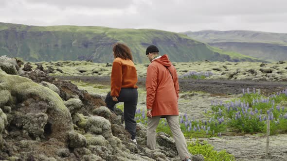 Couple Hiking Up Rocks In Moss Covered Landscape