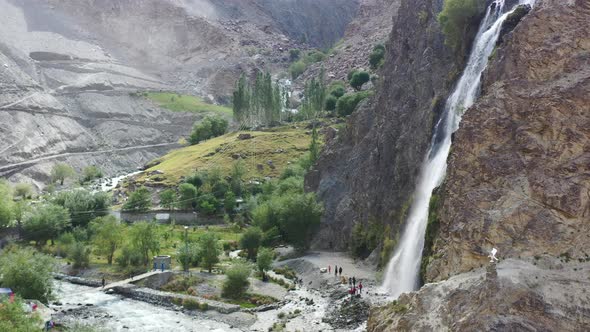 aerial drone panning across left at Manthokha Waterfall in Skardu Pakistan as tourists below are sur