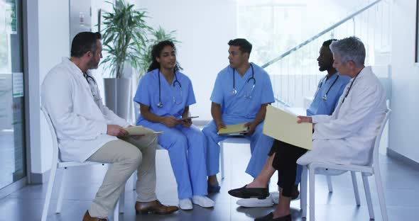 Diverse female and male doctor sitting and discussing at hospital staff meeting
