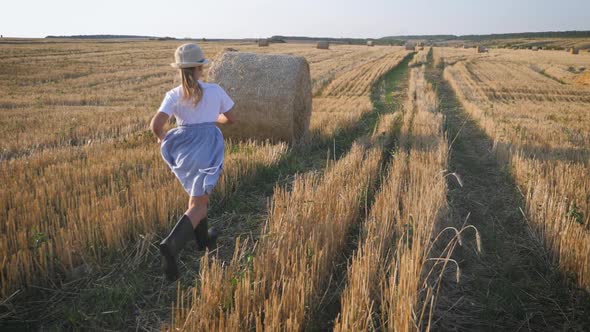 Little Girl in a Field with Haystack Run at Sunset in the Countryside