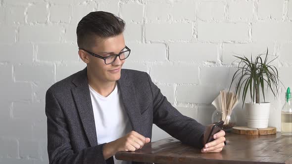 Young Man Using Mobile Phone at Cozy Coffee Shop.