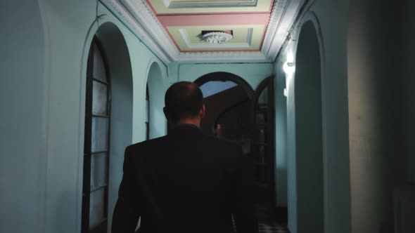 Silhouette of a Man in the Dark Entrance of a House Walking