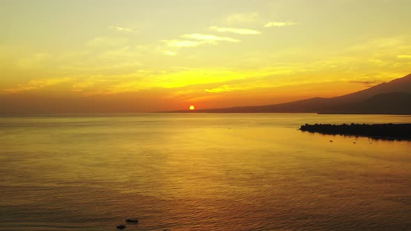 Yellow sun setting down the horizon during golden sunset with bright sky reflecting on calm sea surf