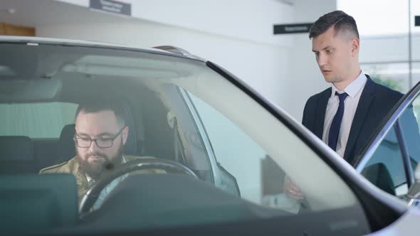 an Adult Man Sits in the Salon of a New Car in a Dealership