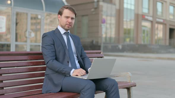 Rejecting Businessman in Denial While using Laptop Sitting Outdoor on Bench