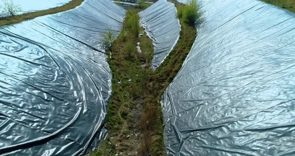 View from above of the sides of garbage dump hill covered with protective film.